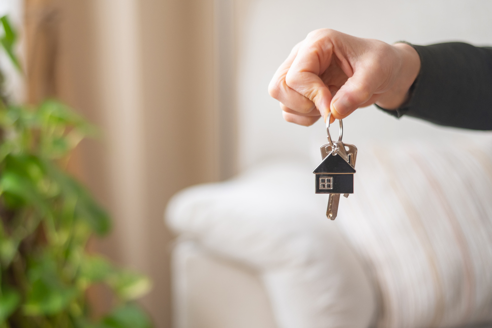 Real estate agent is holding keys of new home, symbolizing property purchase, mortgage approval, or rental agreement in a bright, modern apartment setting